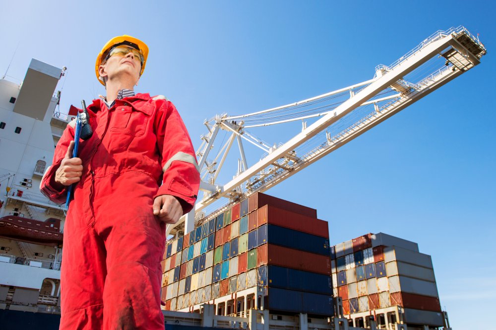 This image features a low-angle shot of a person standing near cargo ship