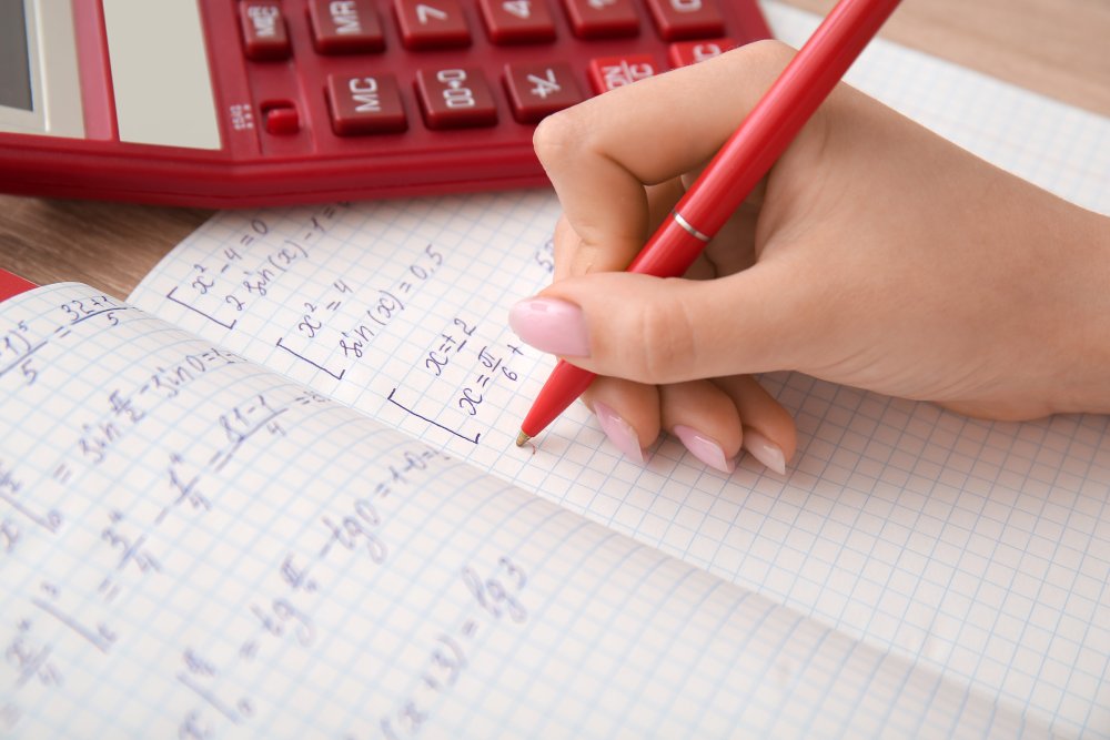 Close Up Photo of Woman writing math formulas in copybook