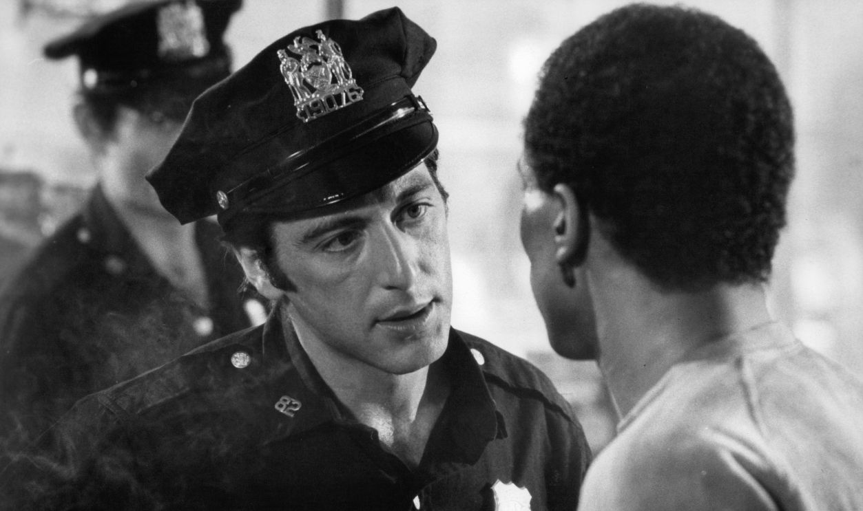 Al Pacino, dressed as a police officer, speaks to a man in a scene from the film 'Serpico', 1973