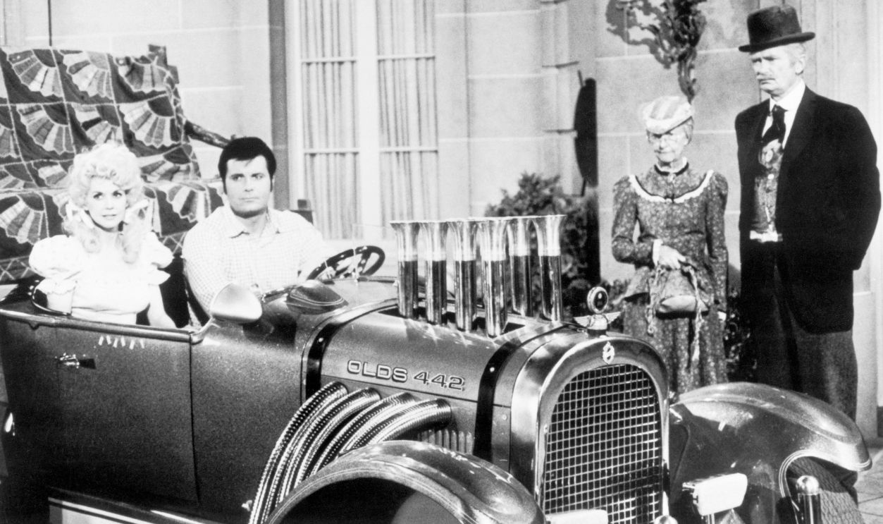  Television still from The Beverly Hillbillies. In this scene, Donna Douglas as Elly May and Max Baer, Jr., as Jethro Bodine are seated in an automobile. Irene Ryan as granny and Buddy Ebsen as Jed Clampett are standing beside them.
