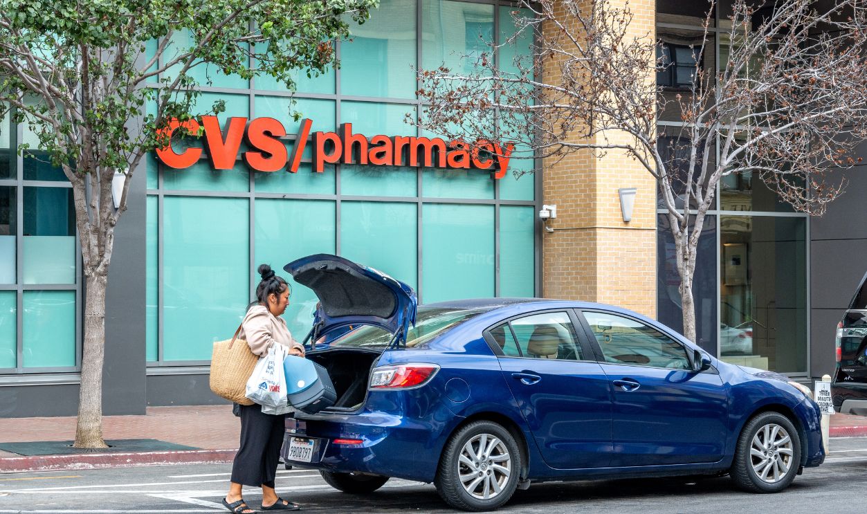 Customer loading shopping bags into car trunk after visiting CVS pharmacy