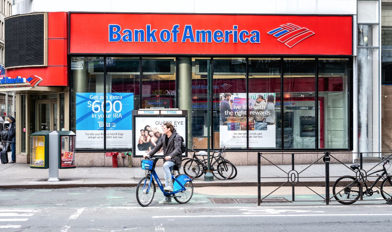 Street view on Bank of America branch in NYC with people waiting, pedestrians crossing, crosswalk, bike, road in Manhattan
