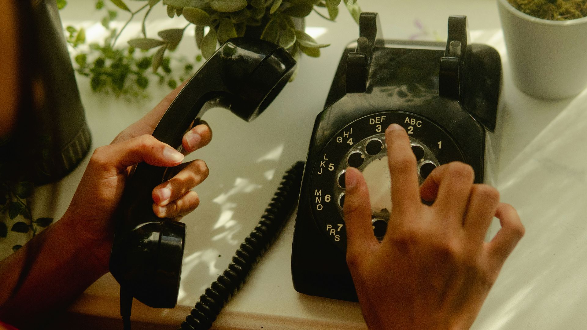 person holding black rotary telephone