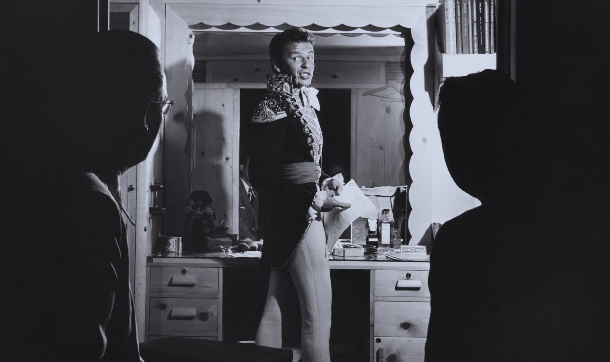 American actor and singer Frank Sinatra (1915 - 1998) talking to Bobby Burns (left), manager of Tommy Dorsey's band, and publicist Jack Keller, in a dressing room, 1948. He is in costume for his role in 'The Kissing Bandit', directed by Laslo Benedek.