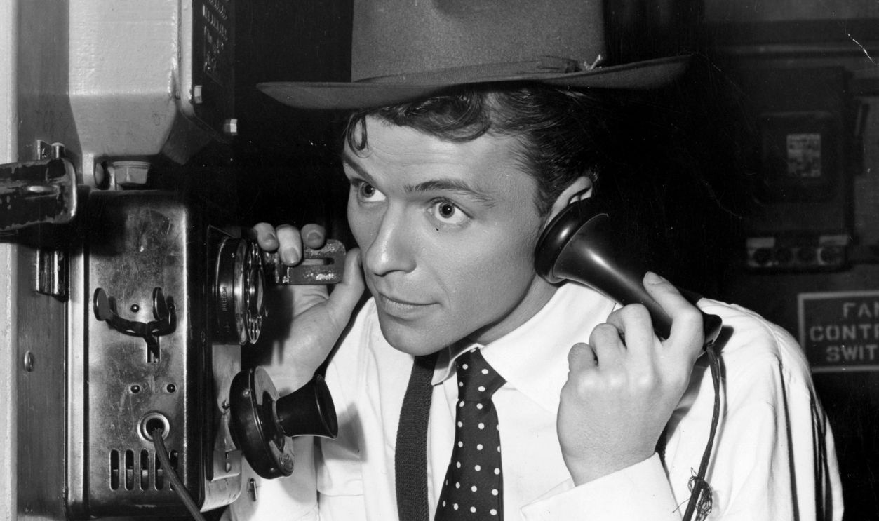 circa 1940: A young Frank Sinatra making a telephone call on the set of the film 'Step Lively'.