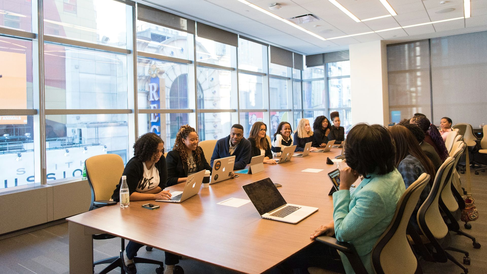 group of people sitting beside rectangular wooden table with laptops