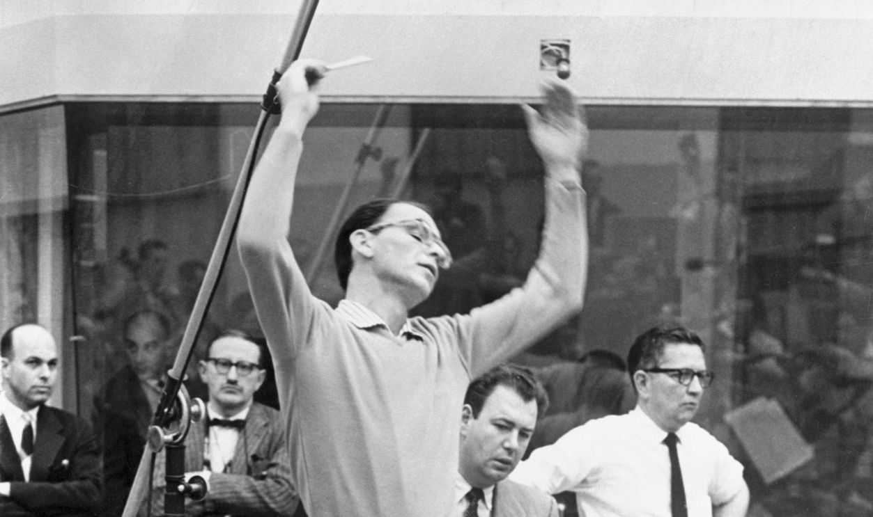 Frank Sinatra Directing Orchestra Actor and singer Frank Sinatra made the second appearance of his career as a conductor recently when he raised the baton in Hollywood's new Circular Tower building to conduct a 56 piece orchestra in the first recording disk session in the new building. (Left) Sinatra leading the orchestra. To his left is Nelson Riddle and far right is repertoire director Voyle Gilmore. Center: Sinatra and the musicians listen to the first 