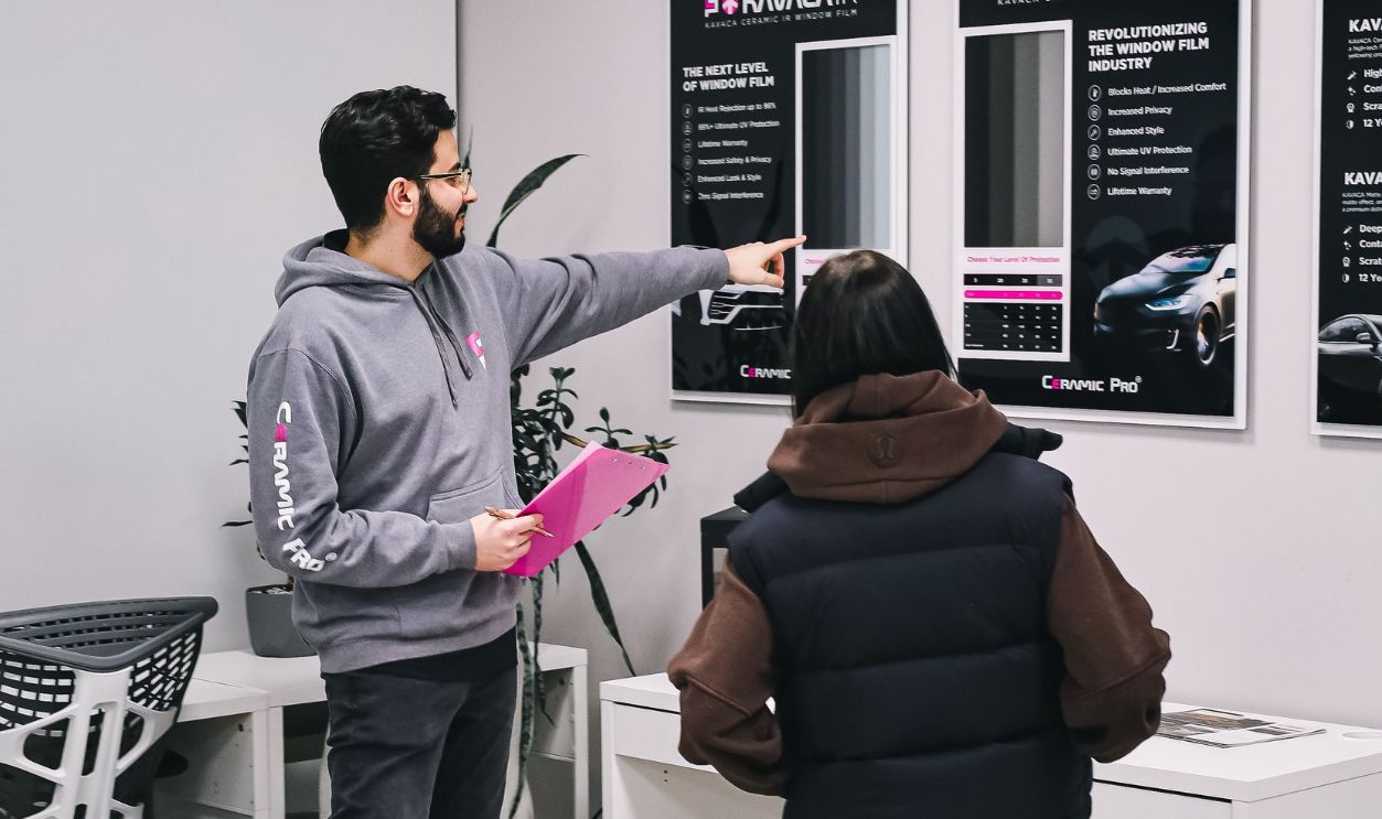 Man and woman discussing service in a car detailing office setting.