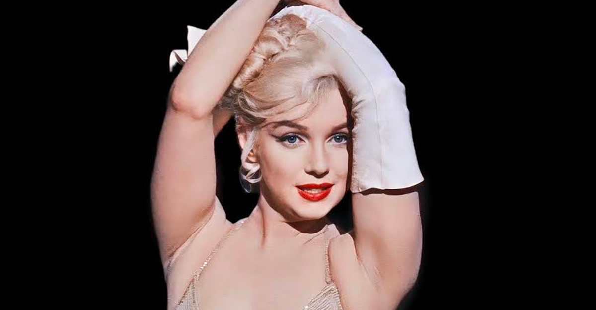 Marilyn Monroe with her arms over her head in a dress with one long glove on one arm in the film Let’s Make Love (1960)