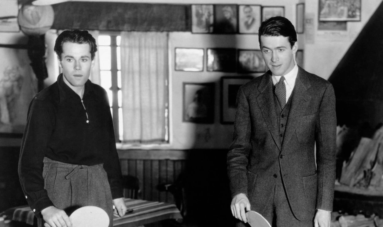 Henry Fonda standing (left) and Jimmy Stewart with ping pong paddles in hand waiting for a volley from a possible opponent. Unknown whether a film or a candid shot. Undated photograph.