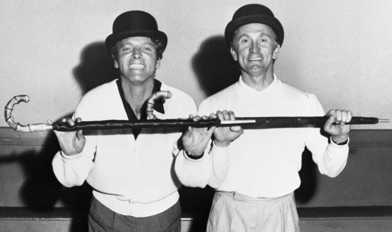 A couple of song and dance men, Burt Lancaster (left) and Kirk Douglas (right) polish up their routine in London for a special benefit show. Sporting British bowlers and rolled umbrellas, they're taking time out from rehearsals for the screen version of George Bernard Shaw's "The Devil's Disciple," with Laurence Olivier for United Artists release. The two stars did a similar song and dance number at this year's Academy Awards ceremony.