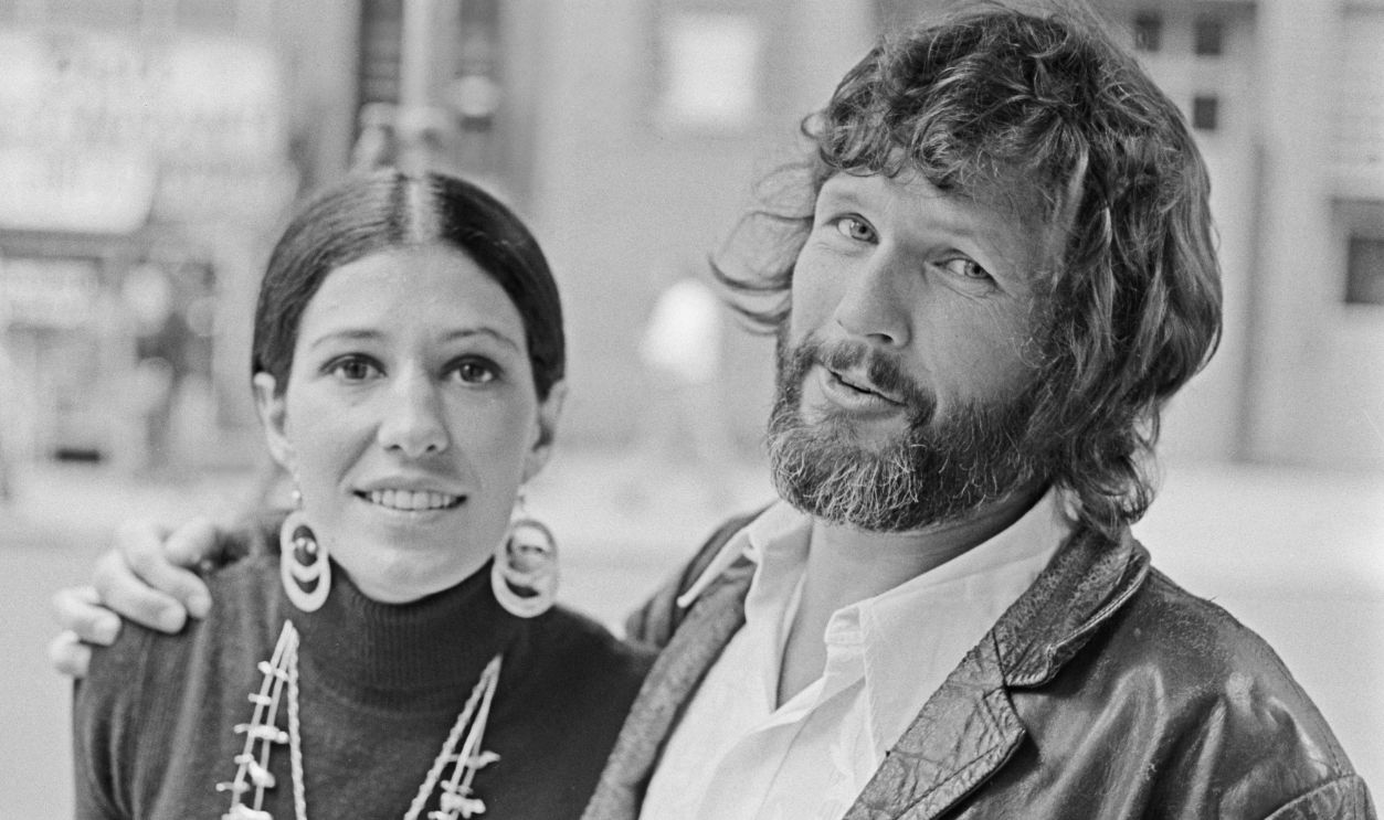 Getty Images - 1319765156 - American singer Rita Coolidge, wearing a black turtleneck sweater with double circle earrings and necklaces, with her husband, American singer-songwriter and actor Kris Kristofferson, wearing a leather jacket over a white shirt, open at the collar, location unspecified, 6th November 1974.