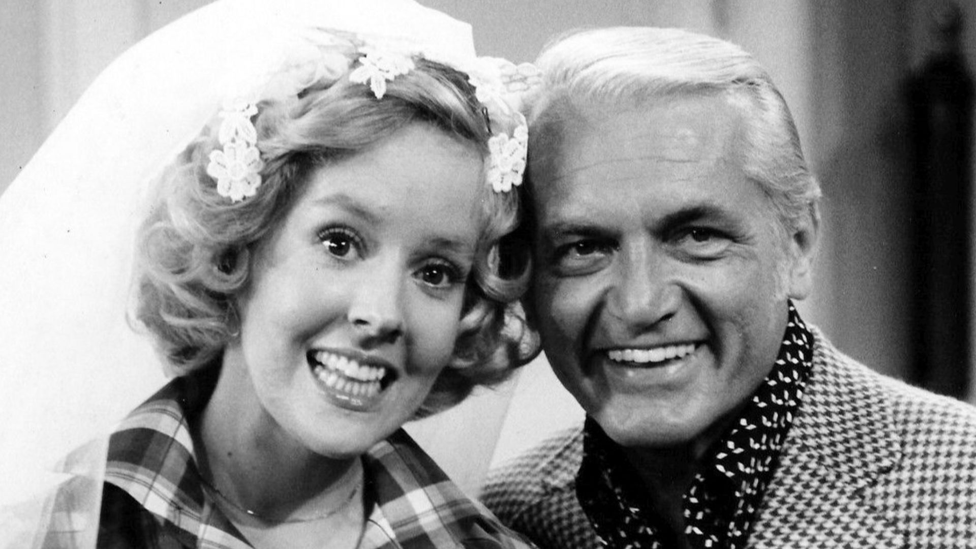 Photo of Georgia Engel and Ted Knight from the television program The Mary Tyler Moore Show.  Georgette Franklin (Engel) and anchorman Ted Baxter (Knight) have just been married at an impromptu ceremony at Mary Richard's (Tyler Moore) apartment.