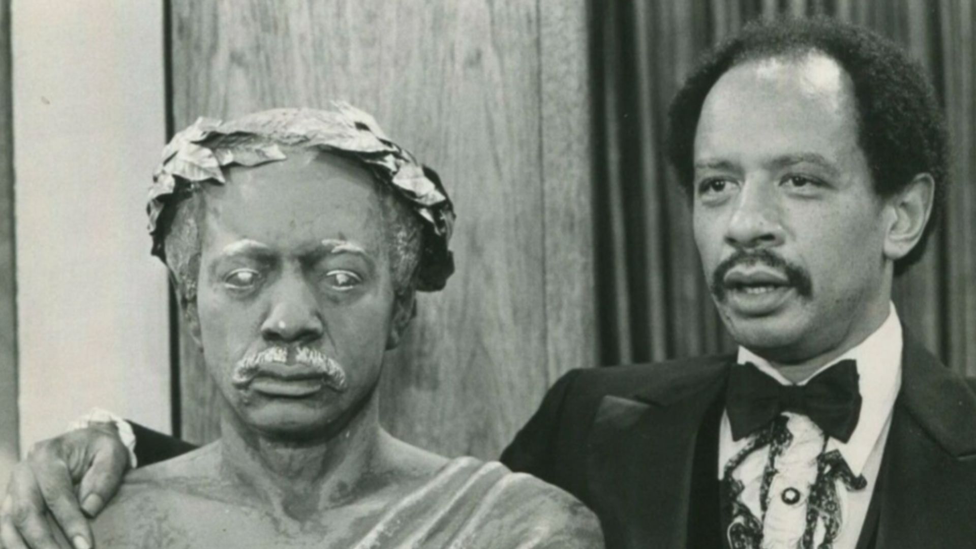 George (Sherman Hemsley), afraid that his trivial accomplishments in life will never be remembered, poses with a bust he commissioned of himself, on