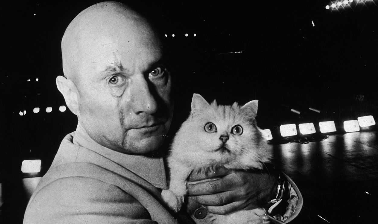 British actor Donald Pleasence (1919 - 1995) in character as Ernst Stavro Blofeld, holding a white cat on the set of the James Bond film 'You Only Live Twice', 24th November 1966