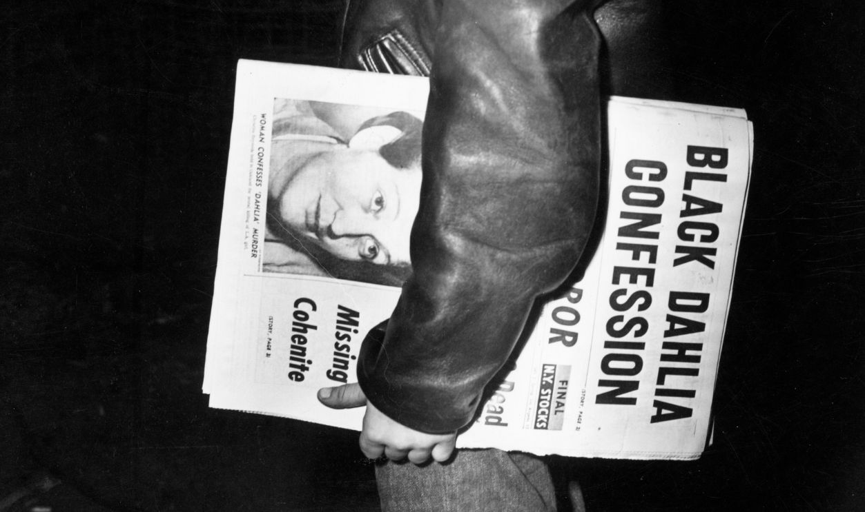 A newspaper boy in New York City, carrying an edition with the headline 'Black Dahlia Confession'. 