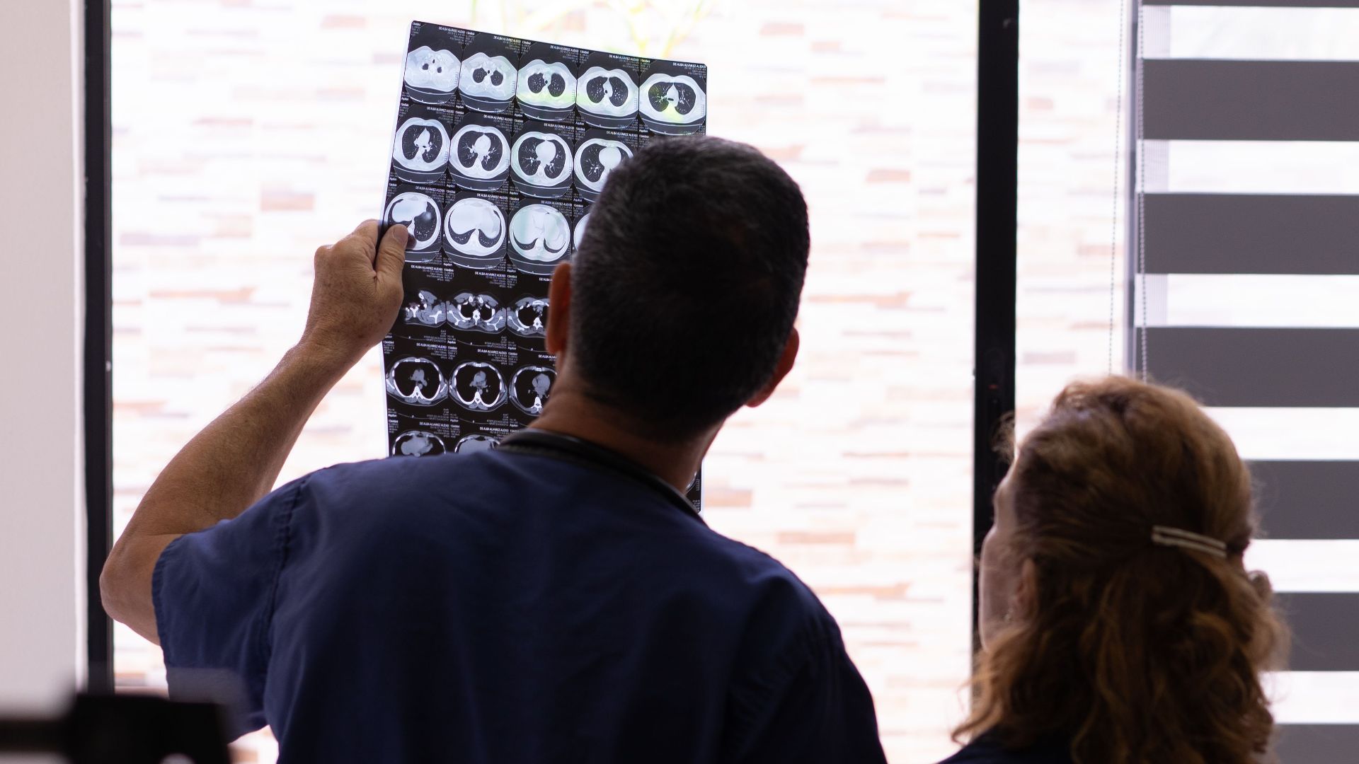 Medical professionals examining an X-ray for diagnosis in a hospital environment.