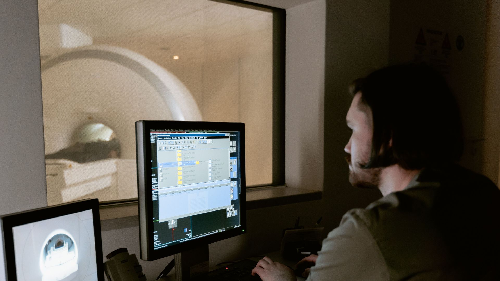 A radiologist examines MRI scan results on computer monitors in a medical facility.