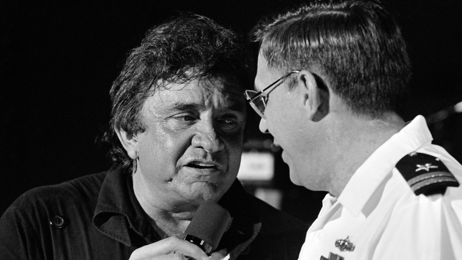 Entertainer Johnny Cash sings a duet with a Navy lieutenant during his performance for military personnel at the naval station.