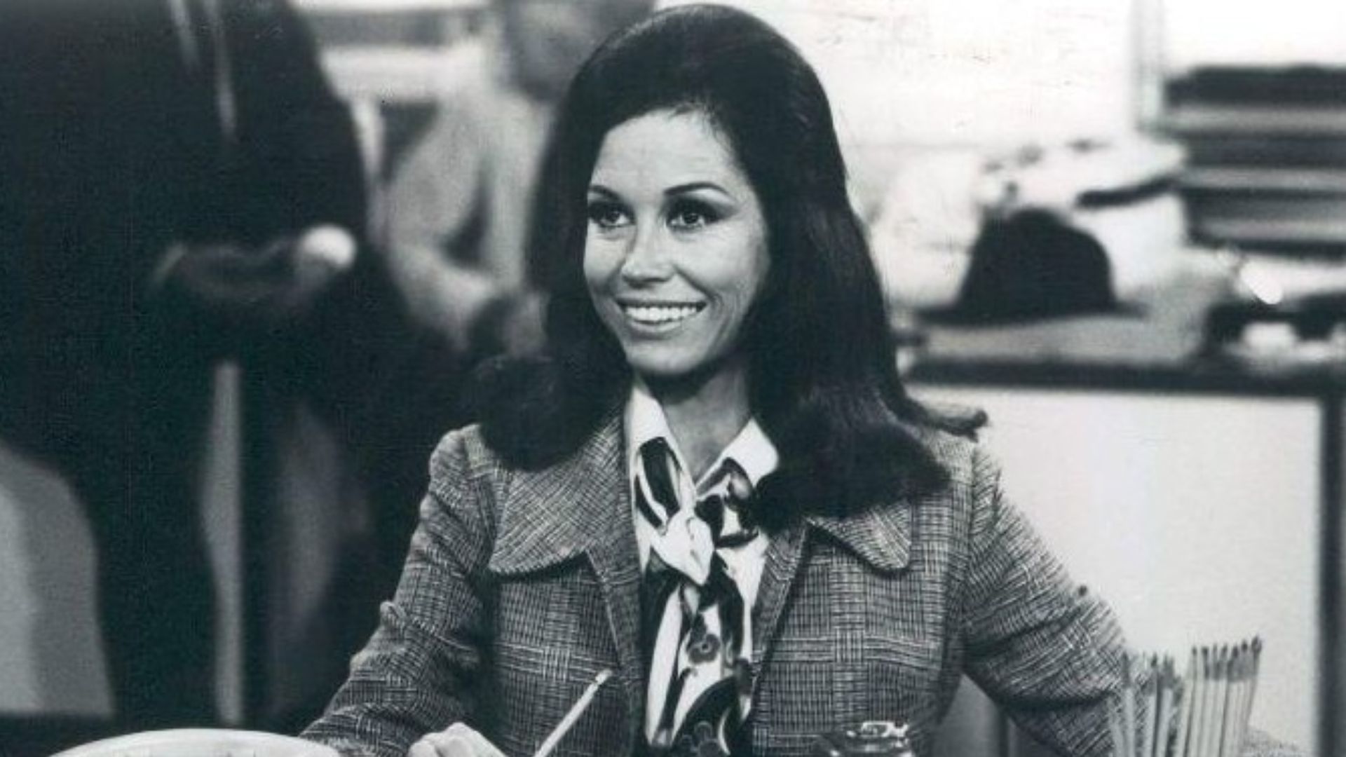 Photo scene from the television program The Mary Tyler Moore Show of Mary Tyler Moore (Mary Richards) at her desk in the WJM-TV newsroom. *Note - this came from a press release dated 1977. The scene is from a 1970 episode.*