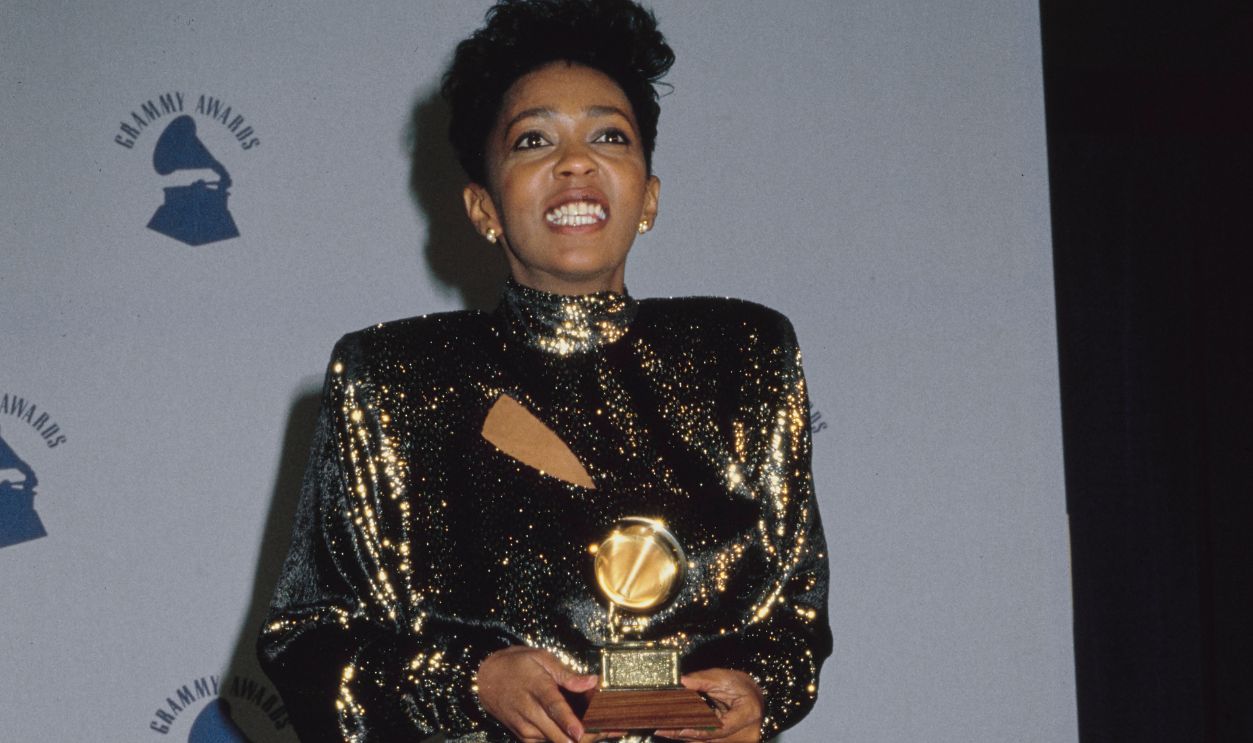 American singer and songwriter Anita Baker, wearing a gold evening dress, in the press room of the 29th Annual Grammy Awards, held at the Shrine Auditorium in Los Angeles, California, 24th February 1987. Baker received two awards at the ceremony: 'Best R&B Vocal Performance (Female)' for 'Rapture' and 'Best Rhythm & Blues Song' for 'Sweet Love.'