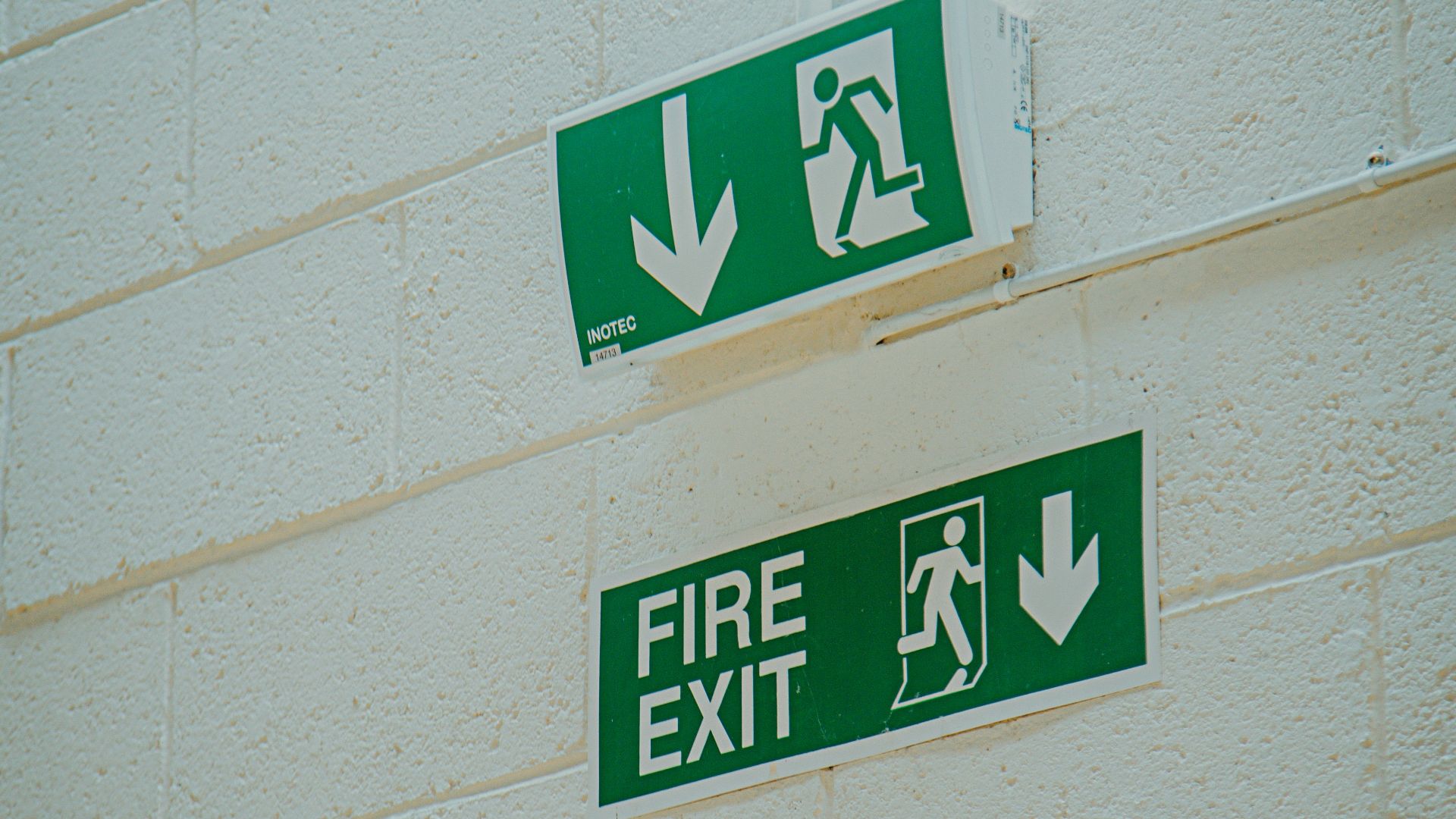 a green fire exit sign mounted to the side of a building