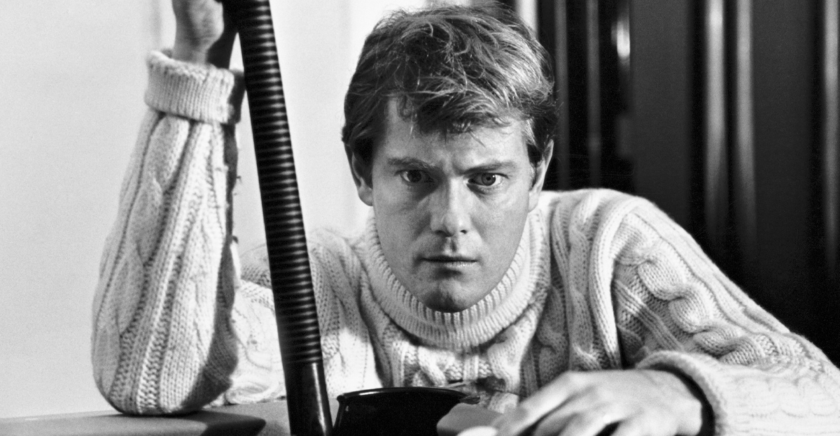 View of American actor Troy Donahue (1936 - 2001), a pool cue in one hand and a cue ball on the other, as he crouches down at the corner of a pool table, Beverly Hills, California, 1966. 