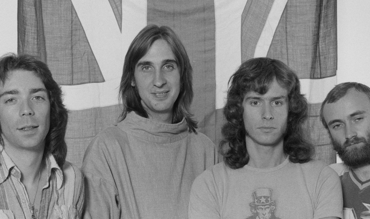 British progressive rock group Genesis posing in front of a union jack flag, 4th September 1975. Left to right: guitarist Steve Hackett, bassist Mike Rutherford, keyboard player Tony Banks and singer/drummer Phil Collins. 