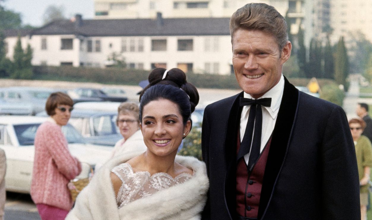 American actor Chuck Connors (1921 - 1992) and his wife, Indian-American actress Kamala Devi (1933 - 2010), attending the wedding of Glenn Ford in Los Angeles, California, March 27th 1966.