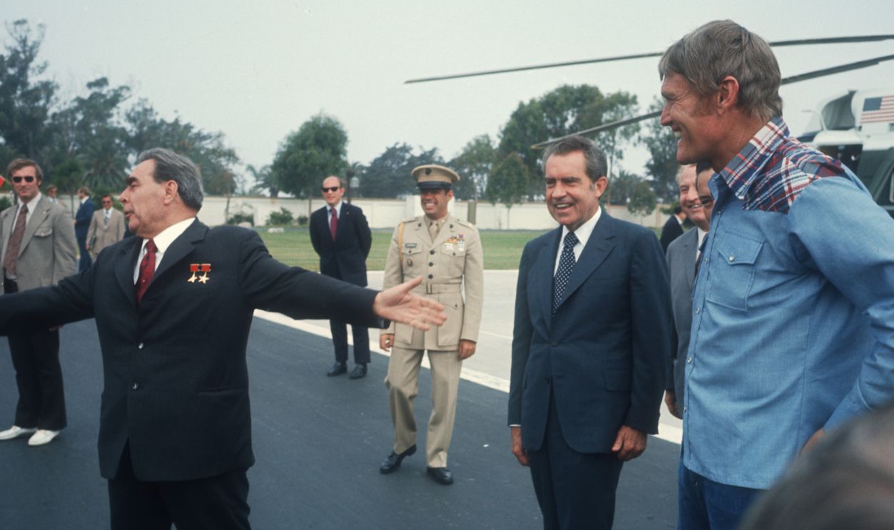 Soviet leader Leonid Brezhnev walks with President Richard Nixon June 20, 1973 at Camp David, MD as famous actor Chuck Connors looks on. Brezhnev met with members of the U.S. Senate Foreign Relations Committee to sign an agreement to prevent nuclear war with the US.