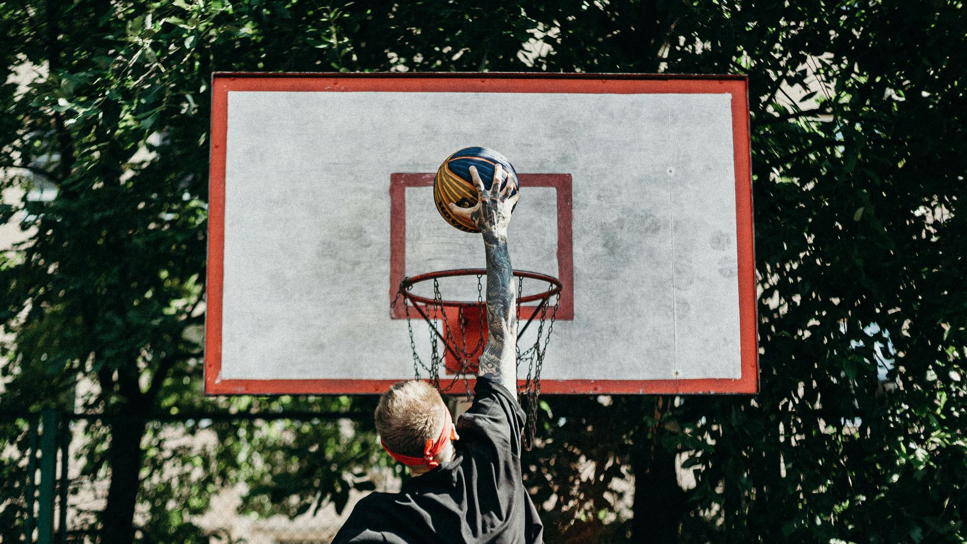 A man jumps to dunk a basketball outdoors, displaying athletic energy and skill.