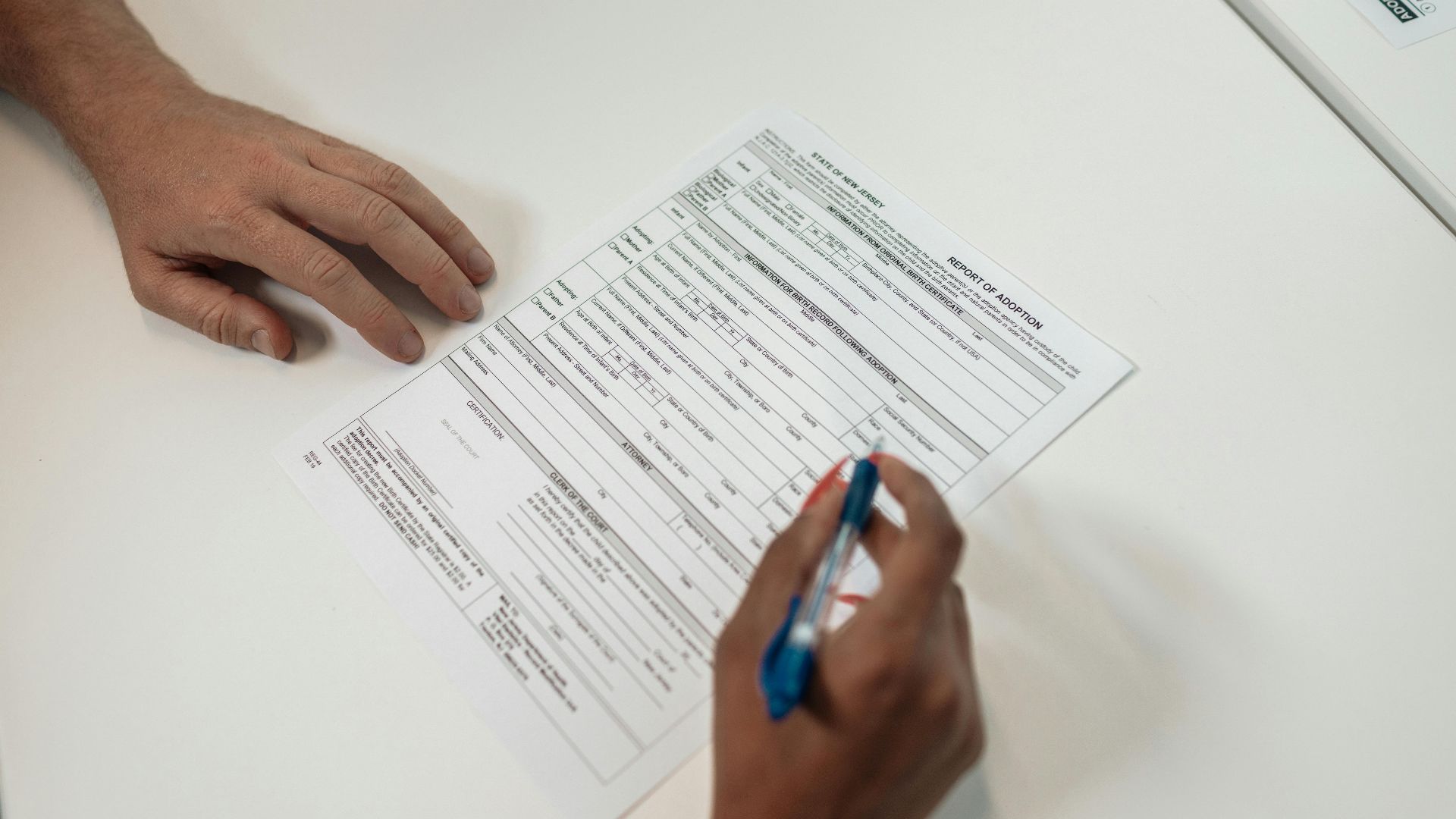Two people reviewing and signing adoption documents, symbolizing legal procedures and family planning.