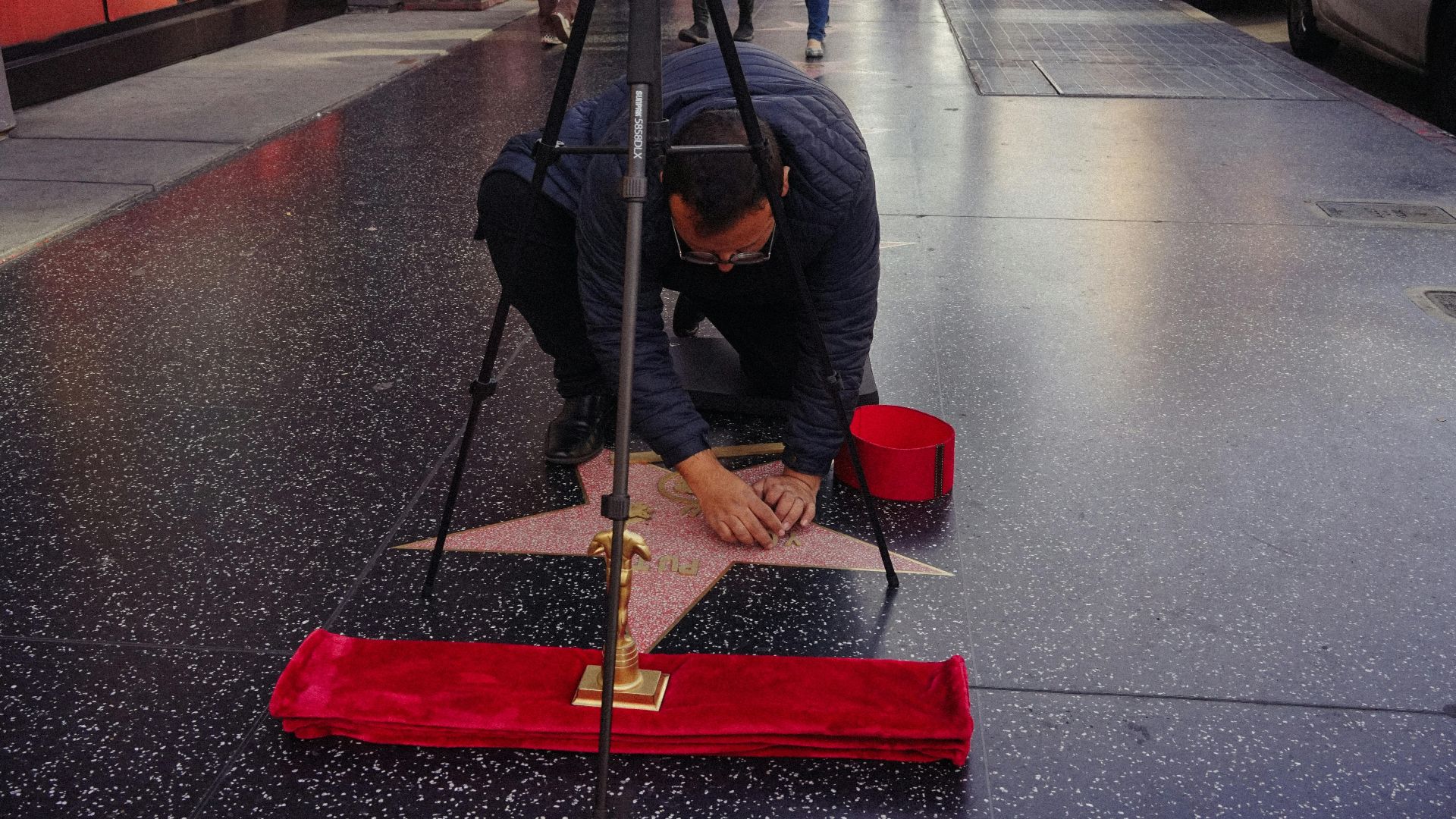 A man meticulously cleans a star on the Hollywood Walk of Fame, symbolizing celebrity culture.