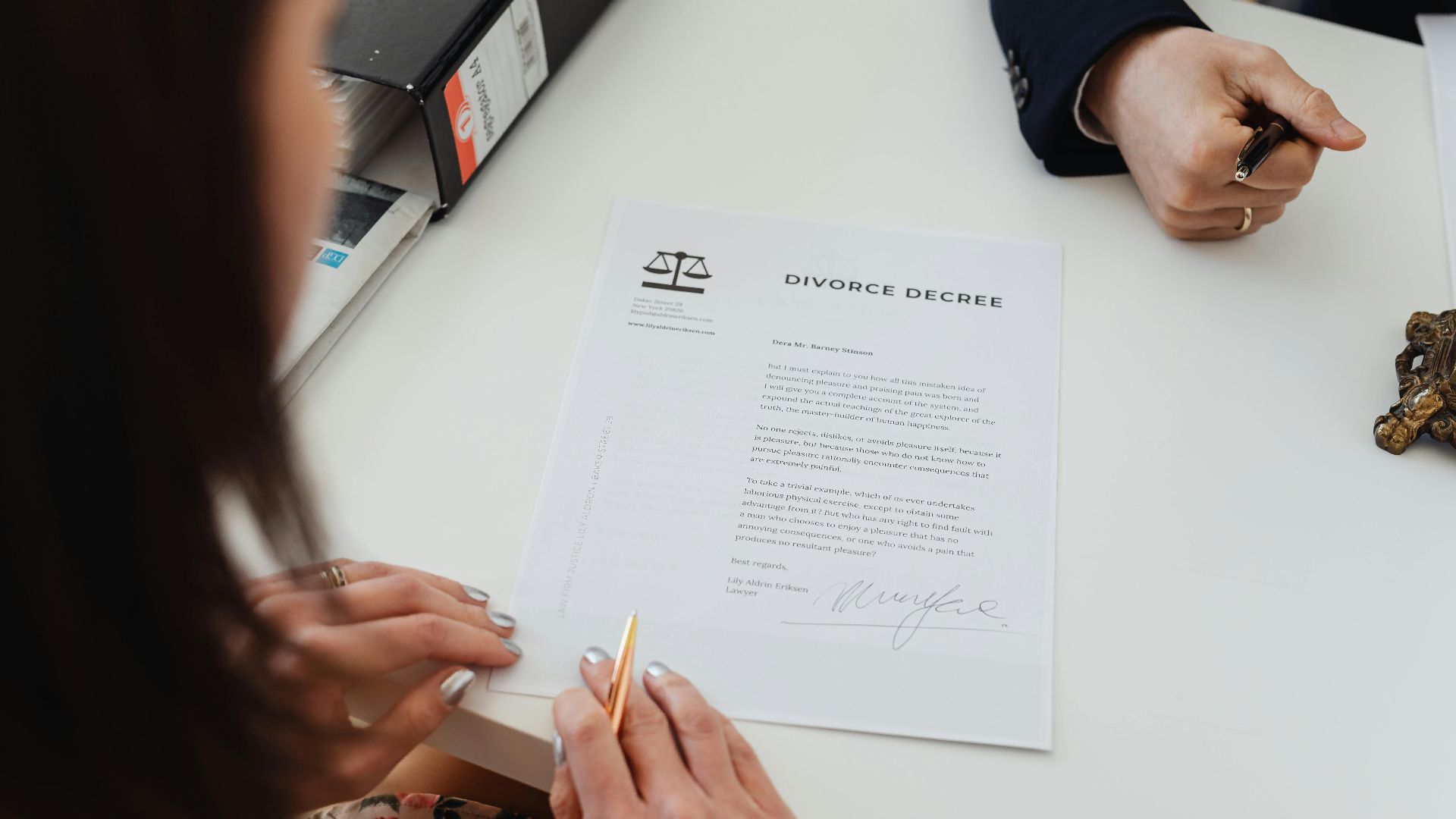 A close-up shot of two people signing a divorce decree at a law office table.