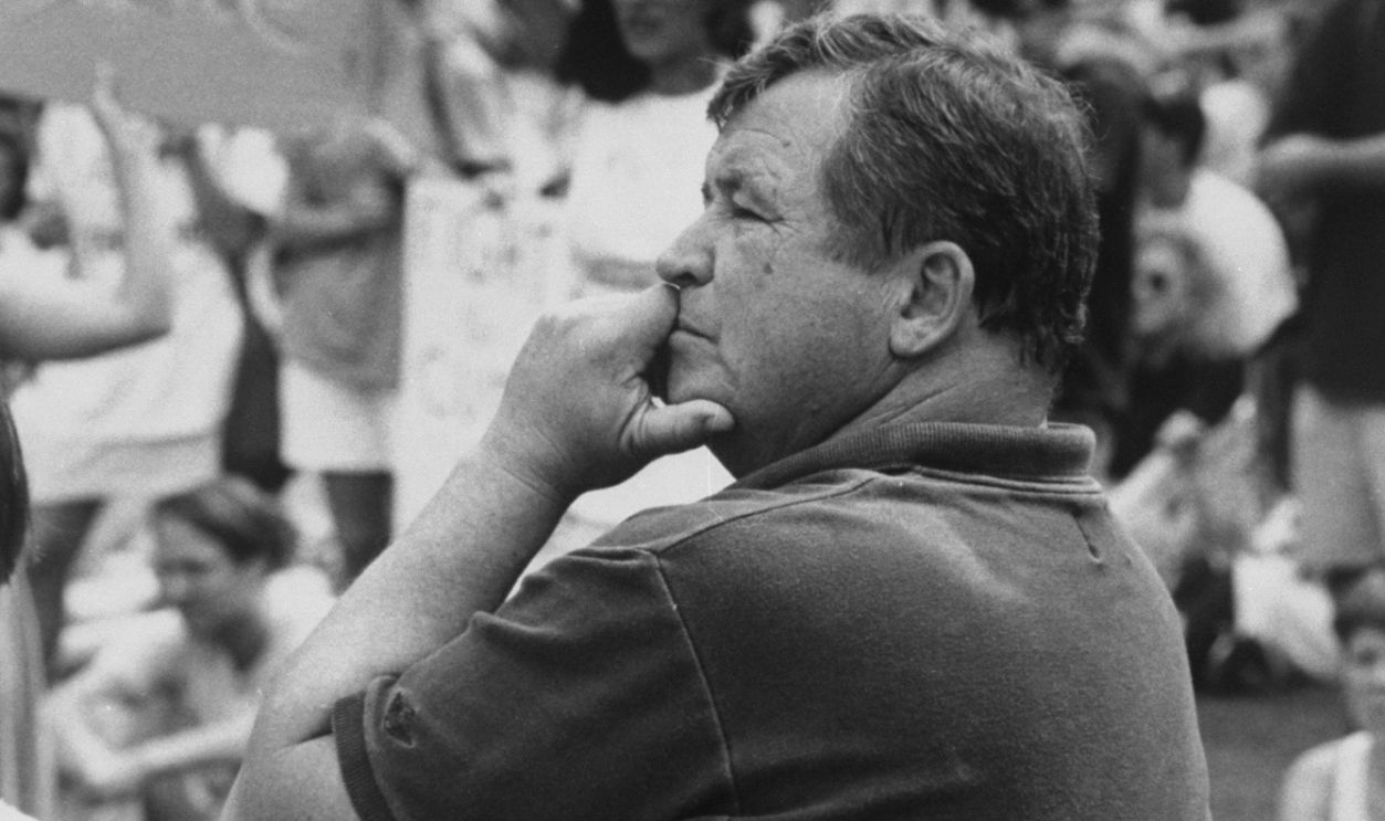 Ex-actor/self-proclaimed pres. cand. Tom Laughlin patiently sitting in folding chair as he waits his turn to speak at a rally of students protesting education budget cuts on the campus of the Univ. of Iowa during his campaign tour of the state. 