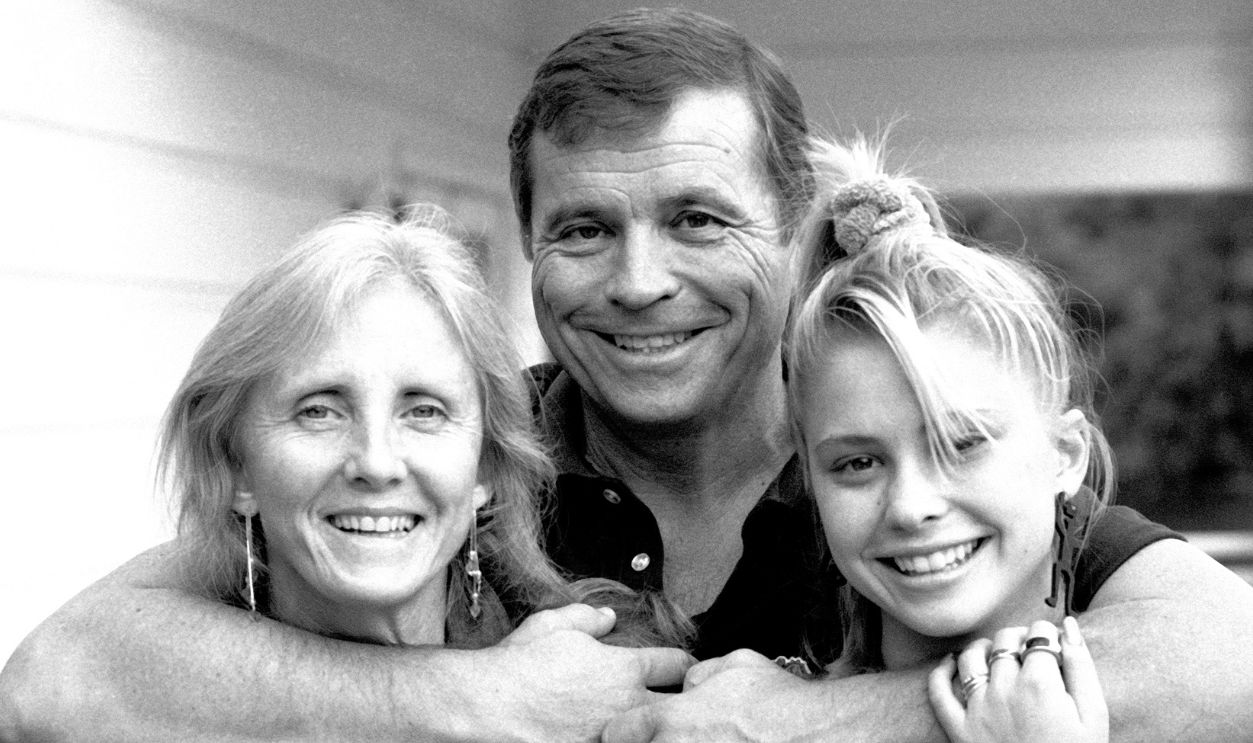 Portrait of American actor Tom Laughlin (1931 - 2013) as he poses with his wife, Delores Taylor, and daughter, Christina, during a photo shoot at his home, Los Angeles, California, November 8, 1985.