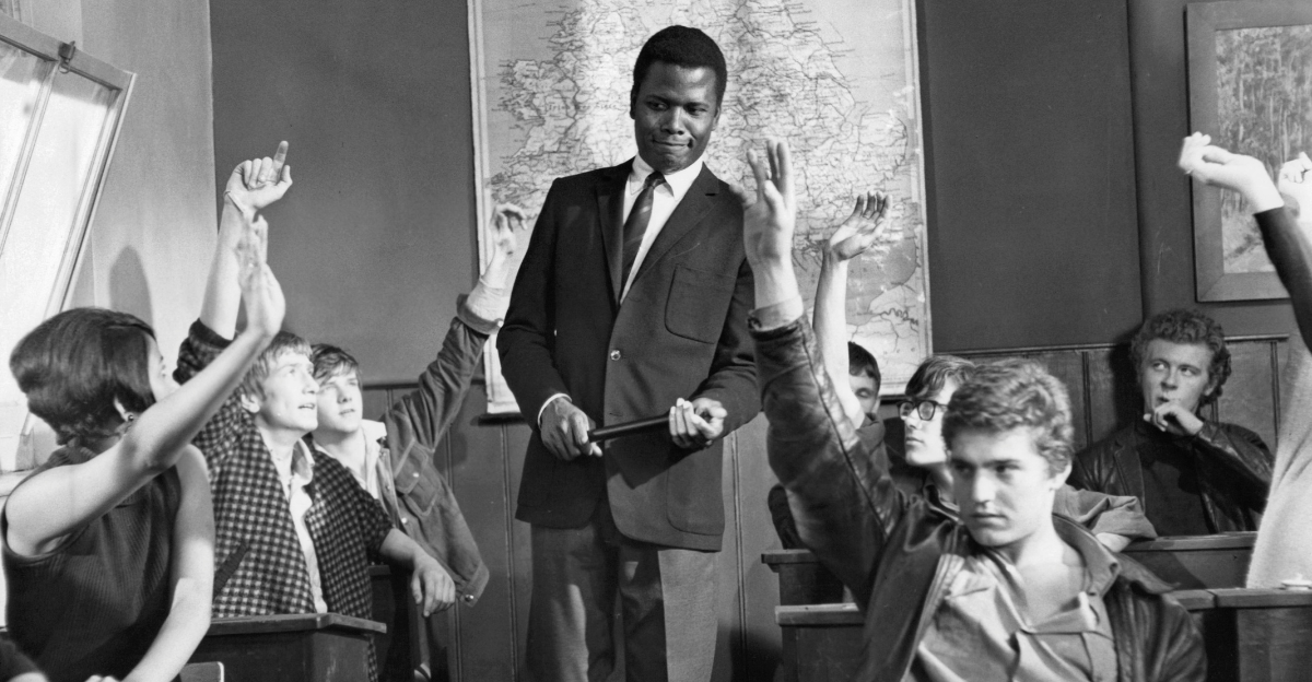 Sidney Poitier standing in classroom as students raise their hands in a scene from the film 'To Sir, With Love', 1967. 
