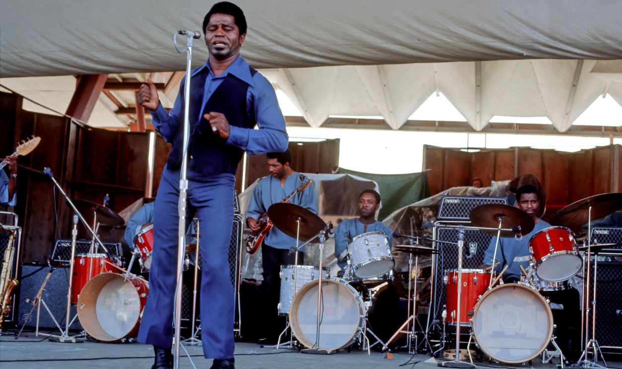 "Godfather of Soul" James Brown performs with 3 drummers at the Newport Folk Festival on July 6, 1969 in Newport, Rhode Island. The license plate reads "B Proud."