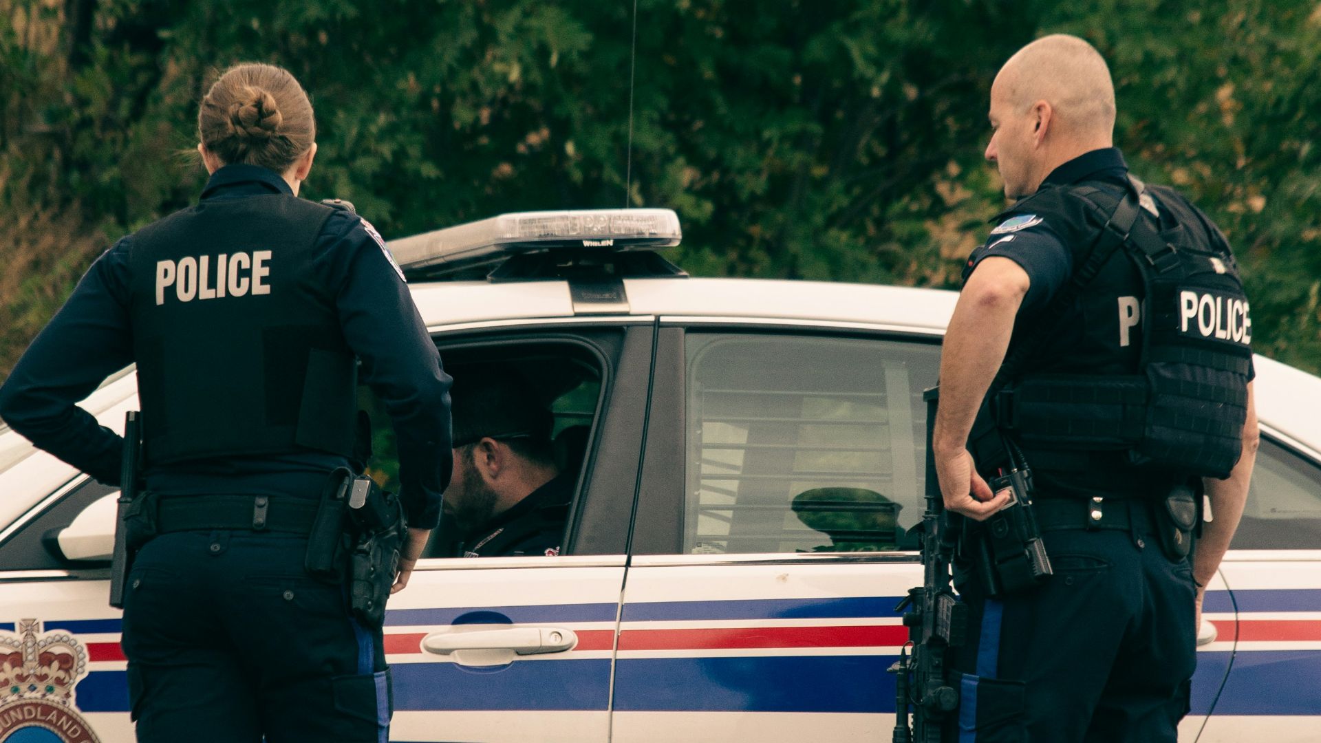 2 police men standing on white police car during daytime