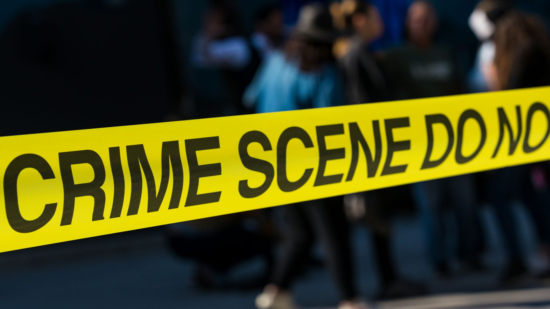 a group of people standing next to a yellow police line