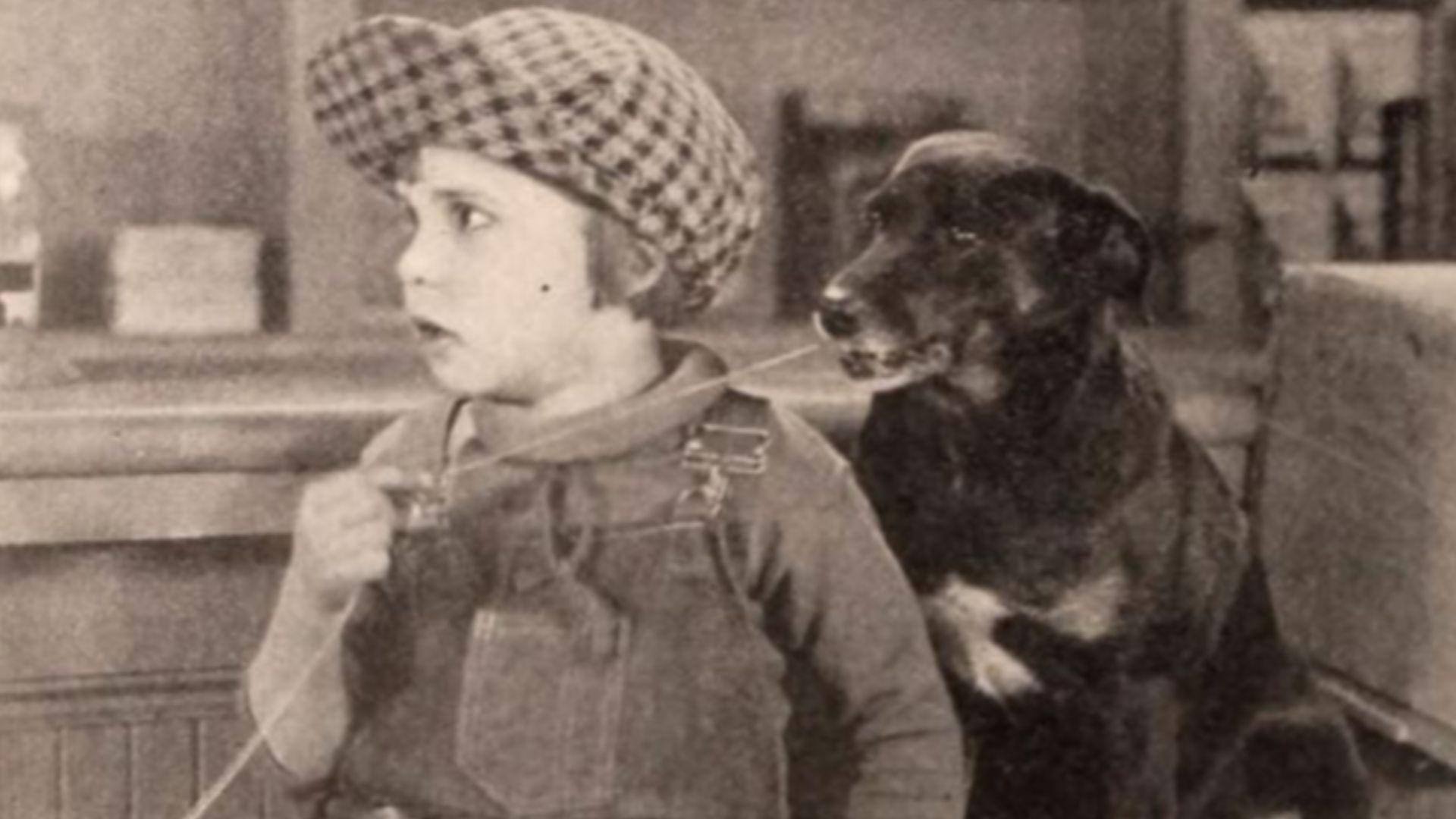 Still from the American film Peck's Bad Boy (1921) with Jackie Coogan with a string to the dog Queenie's tooth, on page 72 of the May 14, 1921 Exhibitors Herald.