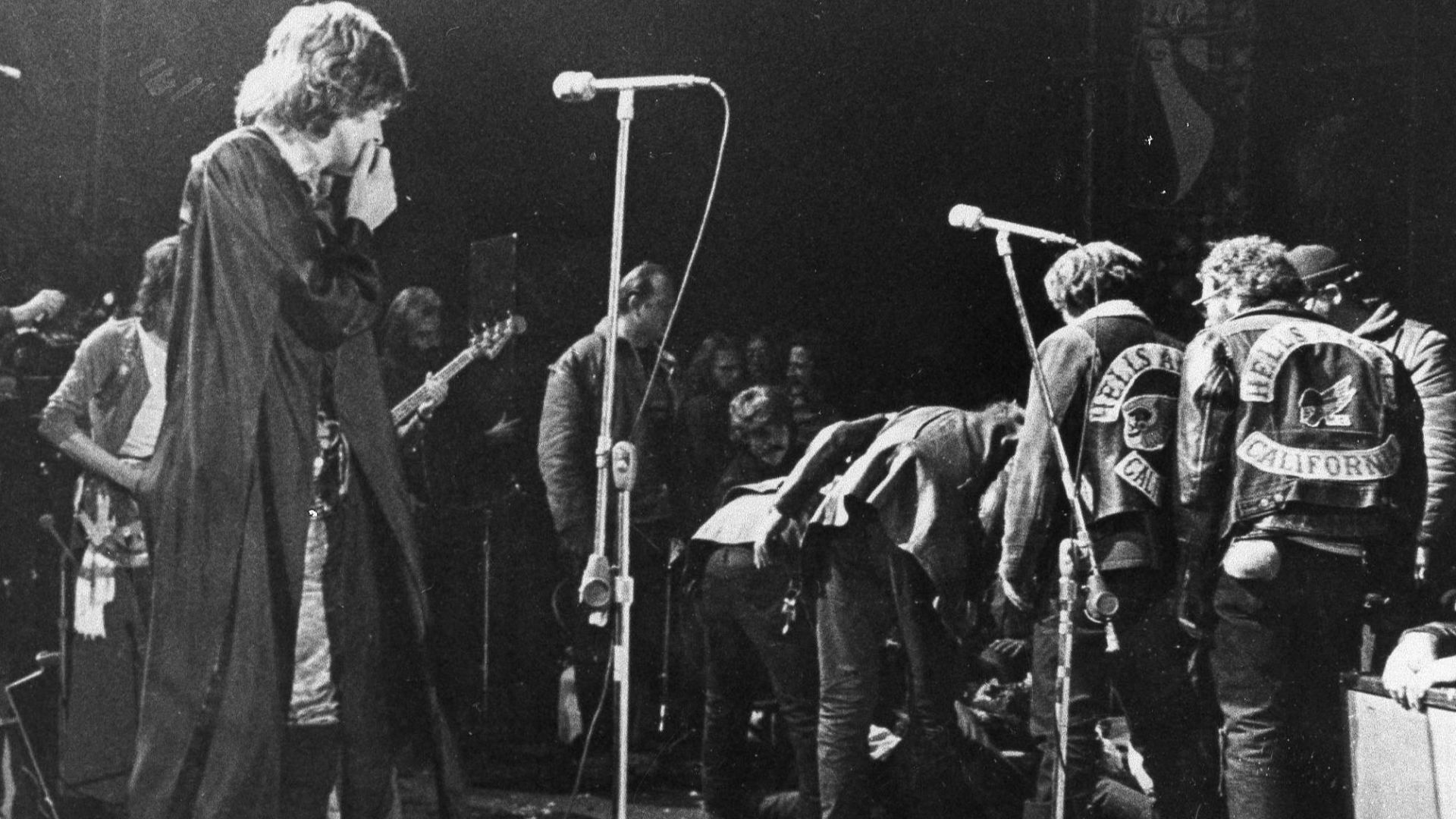 Mick Jagger, on stage at the Altamont Rock Festival on Dec. 6, 1969, watches as Hells Angels cross the stage during a melee to help fellow motorcyclists. The Rolling Stones hired the Hells Angels to police the concert, for $500 worth of beer, but the Angels became violent during the concert. Among other incidents at the concert, the motorcyclists killed one man and dragged another onto the stage and mauled him.