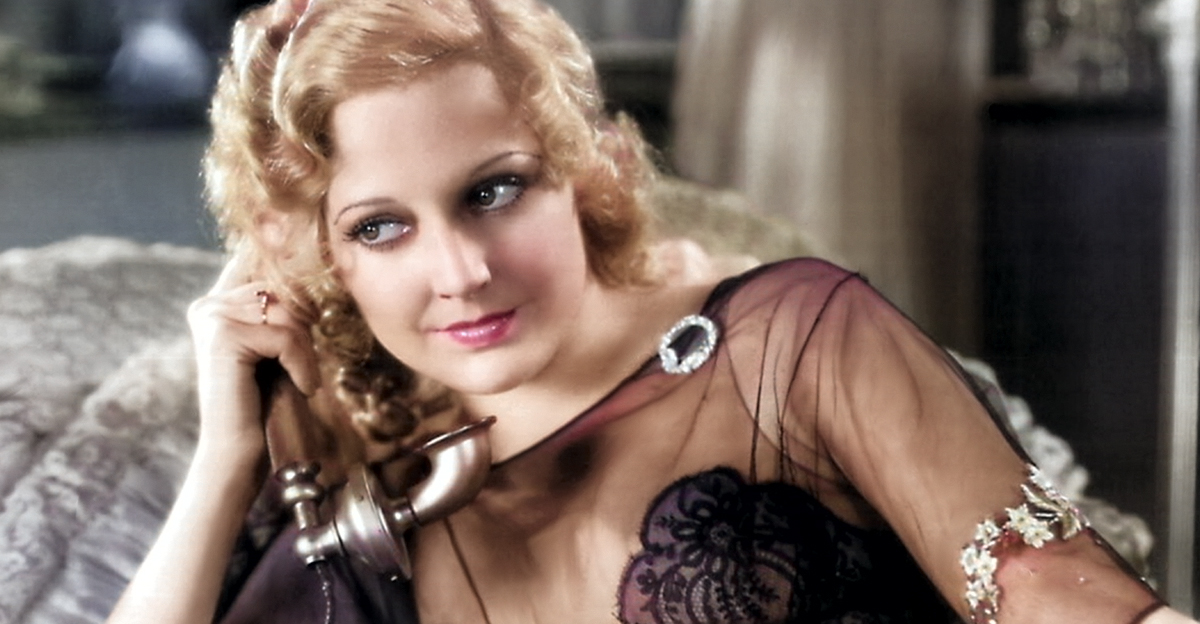 Colorized image of Thelma Todd in a black lacy outfit holding an old phone to her ear.