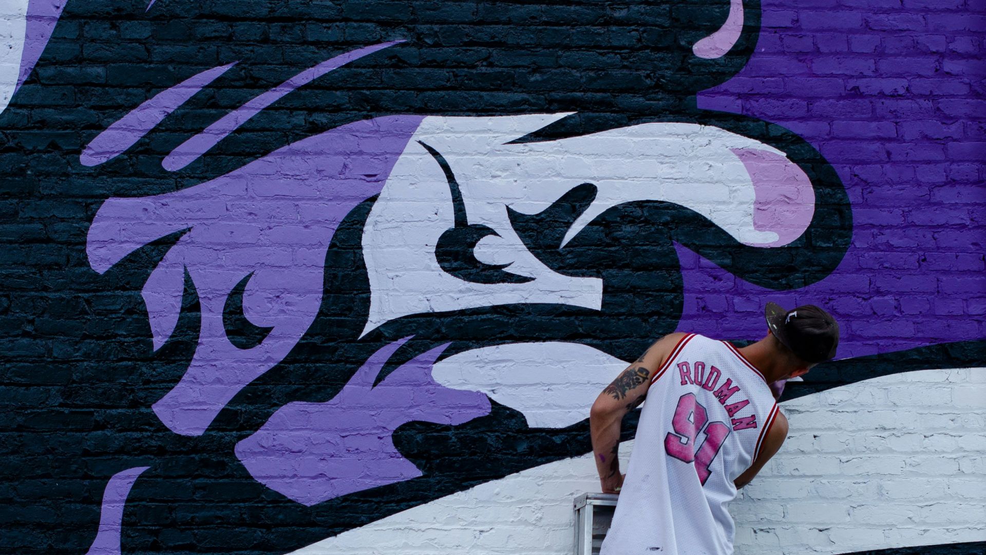 man standing on ladder and painting the wall