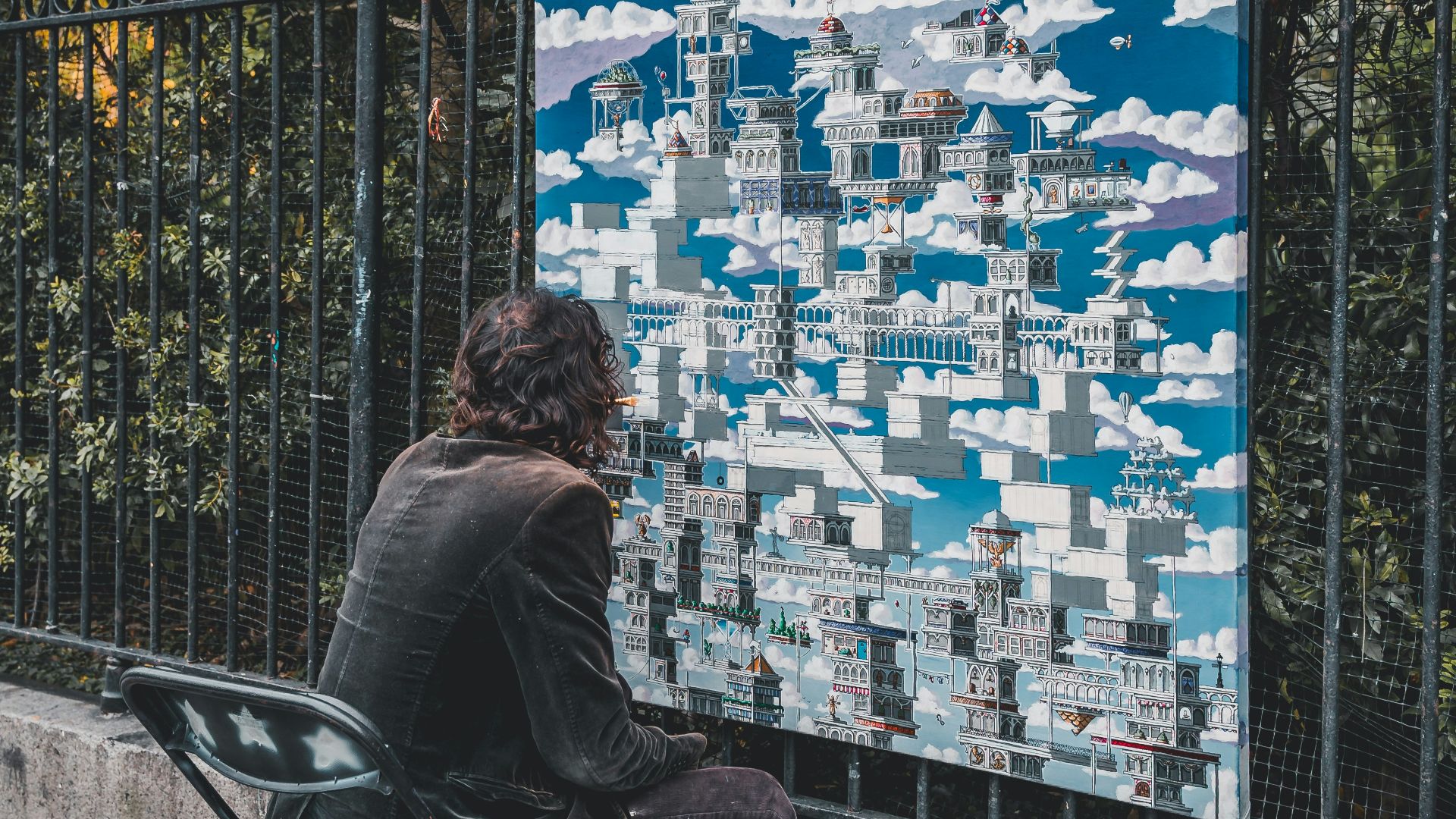 man in black jacket sitting on black chair looking at city buildings during daytime