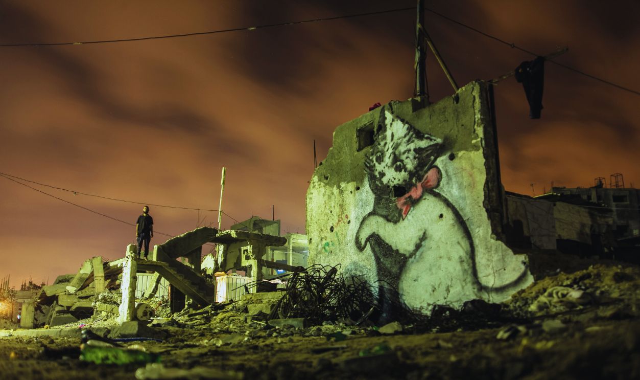   Gettyimages - 524871238, Daily life in Gaza Graffitis are seen on a wall of a building, drawn by British artist Banksy in Beit Hanoun, Gaza Famous British artist Banksy visited Gaza and drew graffiti on the walls of houses in Beit Hanoun destroyed in Israel's recent attacks on Gaza. 