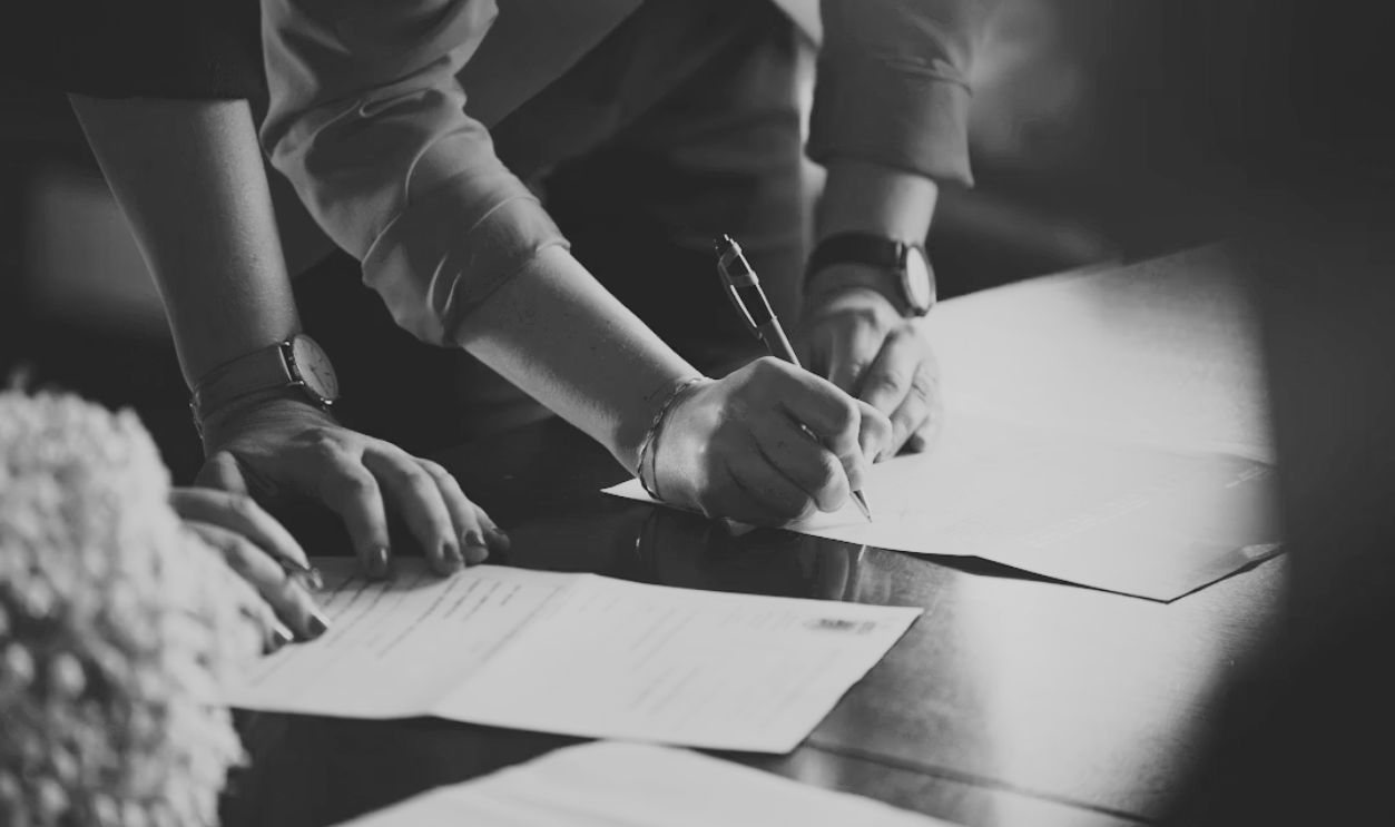 person in orange long sleeve shirt writing on white paper