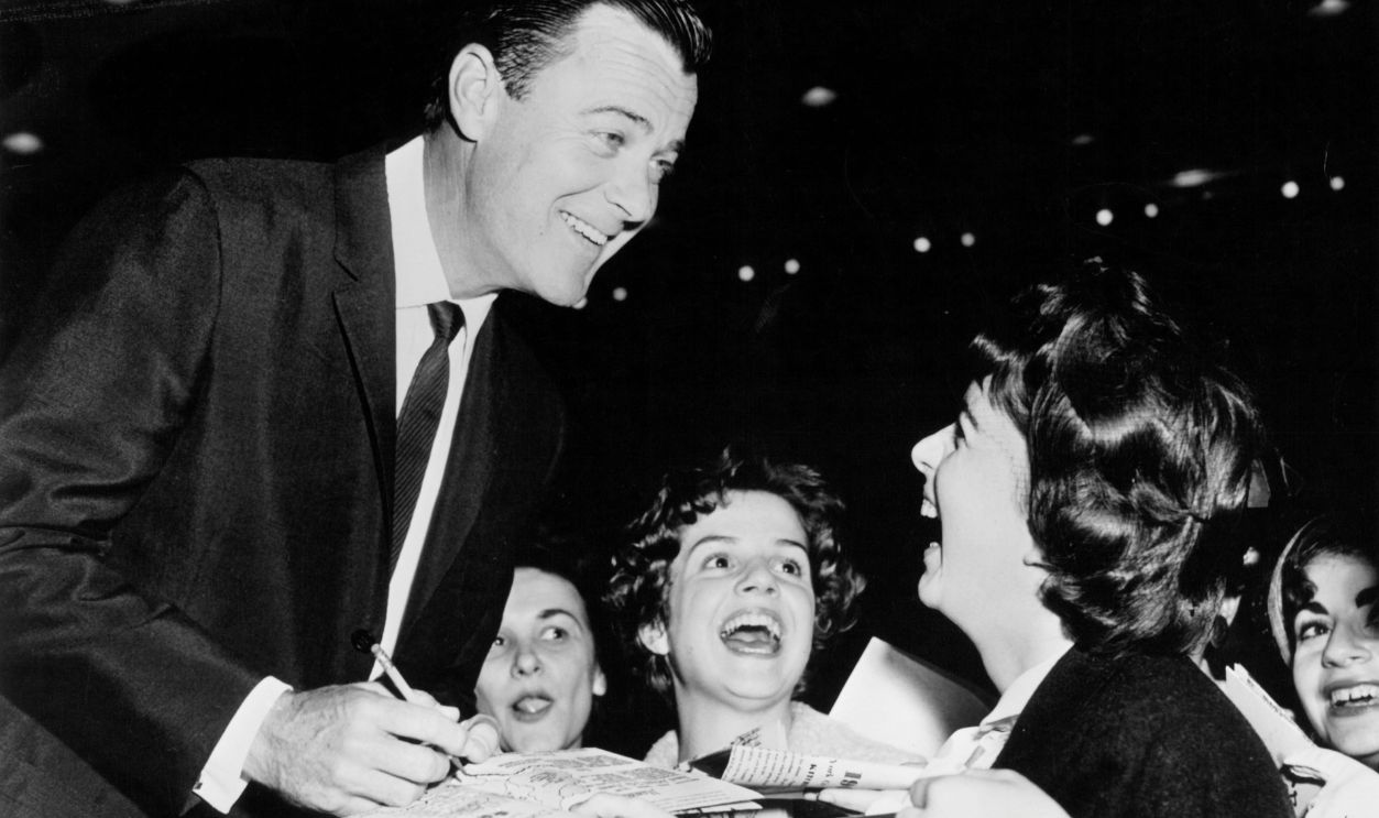 Gig Young signing autographs for screaming fans, circa 1965.