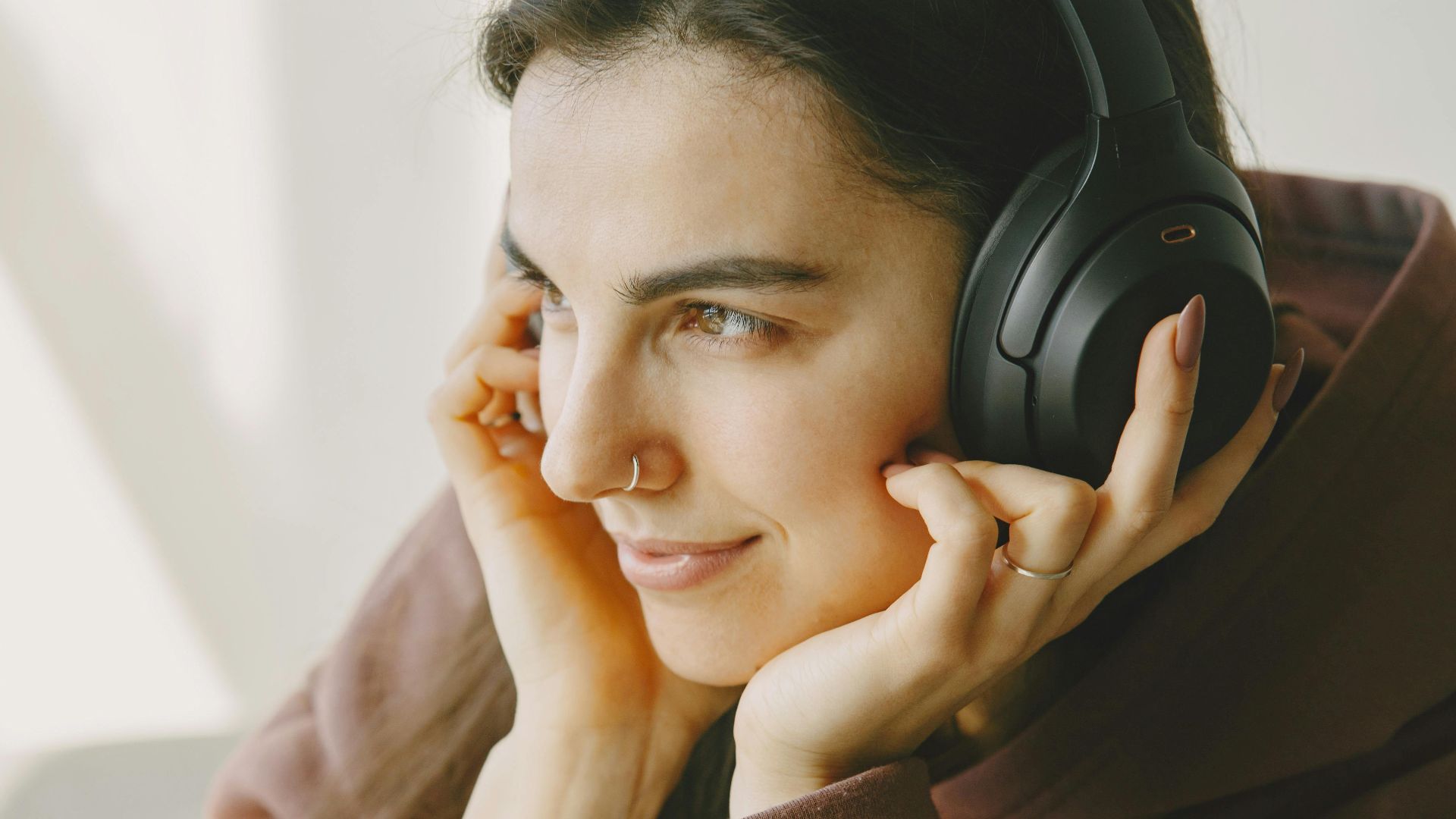 Portrait of a woman relaxing and enjoying music with wireless headphones indoors.