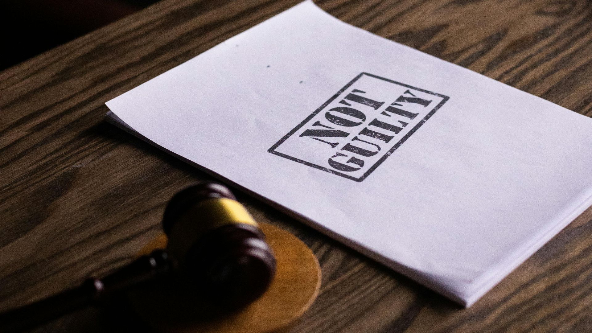 A legal gavel next to a 'Not Guilty' document on a wooden table, symbolizing justice.